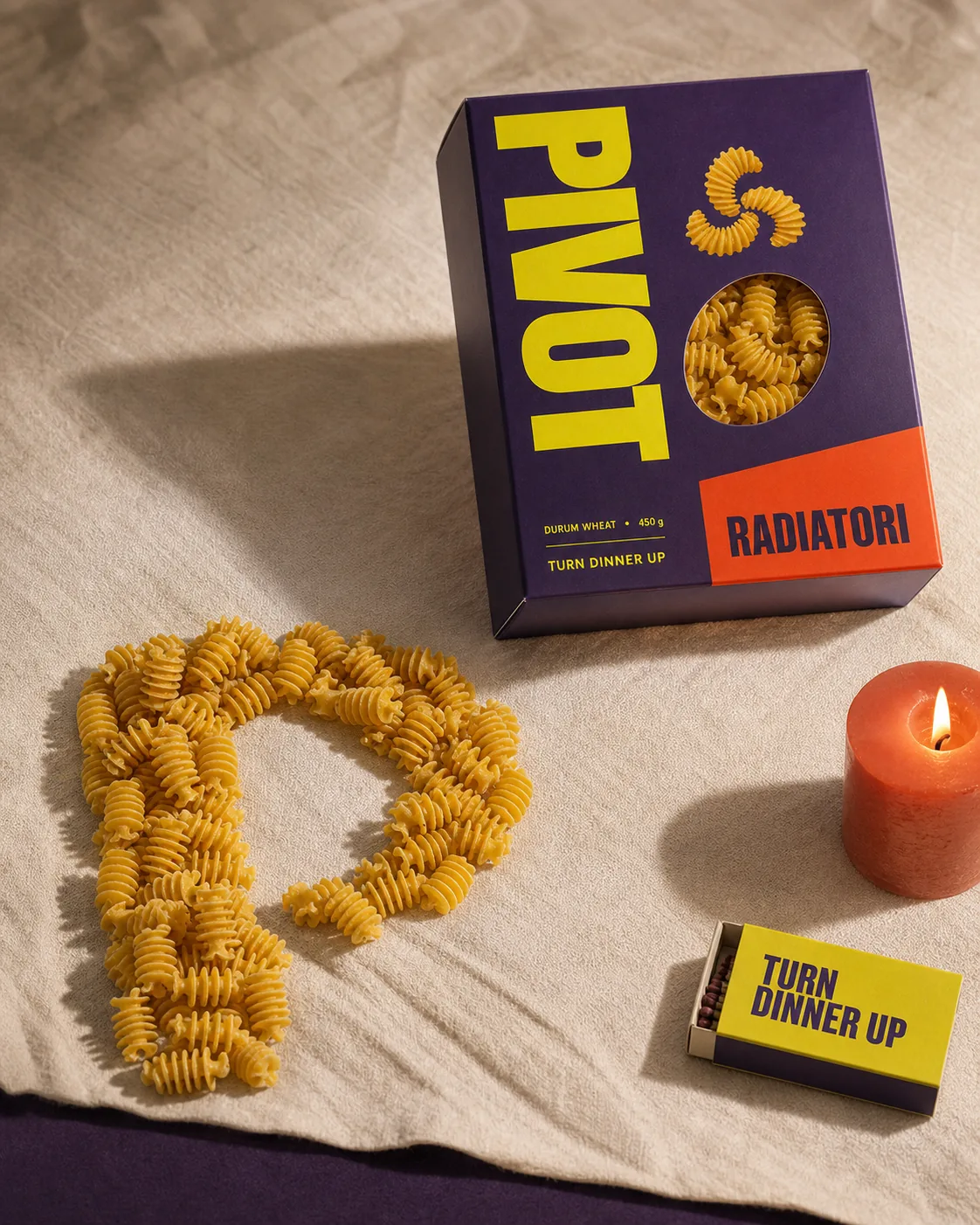Bodegón final de PIVOTE con packaging, pasta y una vela coral